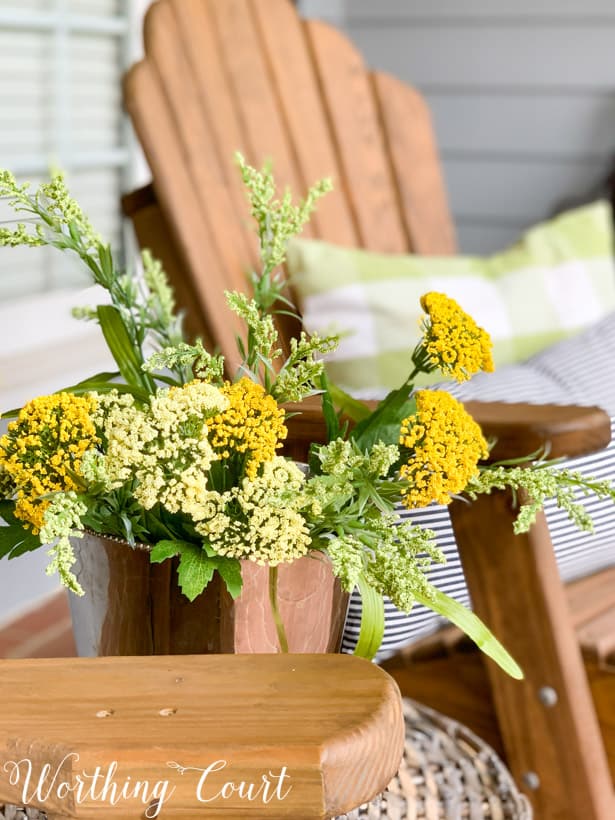 Pretty yellow flowers in a silver pot beside the chairs.