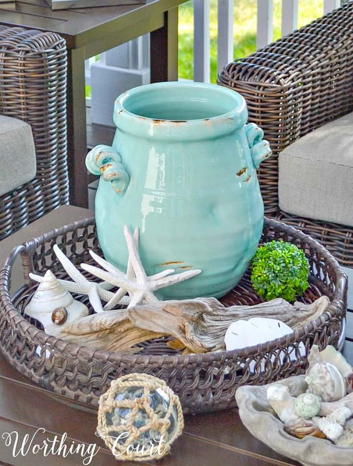 Coastal vignette in a round basket with a blue ceramic vase and starfish.