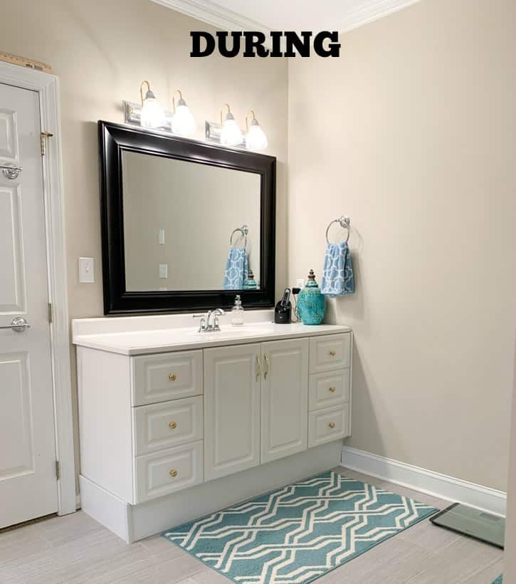 White cabinets and a bold dark mirror in the bathroom.