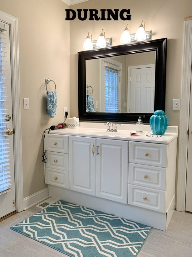 A look at the bathroom during the renovation with a white vanity and blue and white rug.