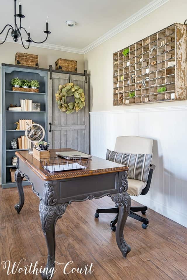 Home office desk, bookcase and chair and a striped throw pillow on the chair.