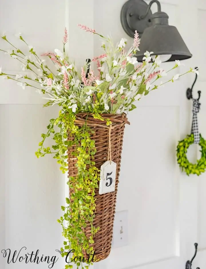 flätkorg fylld med konstgjorda blommor som hänger på väggen