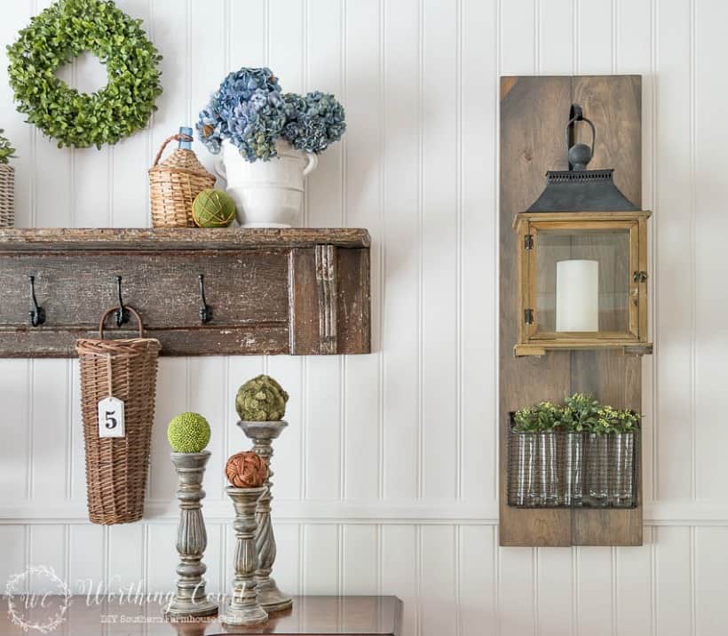 White paneled wall with hanging lantern and vintage shelf display.