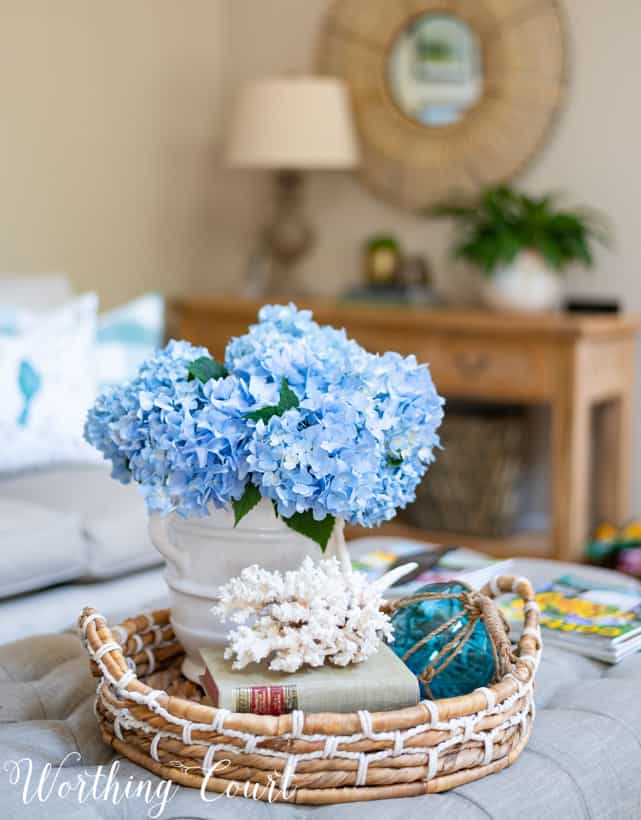 The blue flowers in a white vase in the wicker basket.