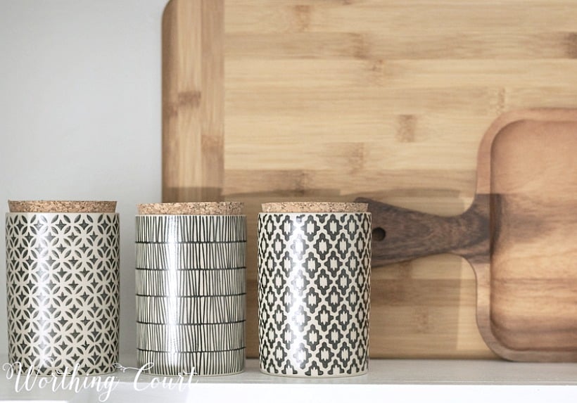 Wooden cutting boards with black and white canisters in front.