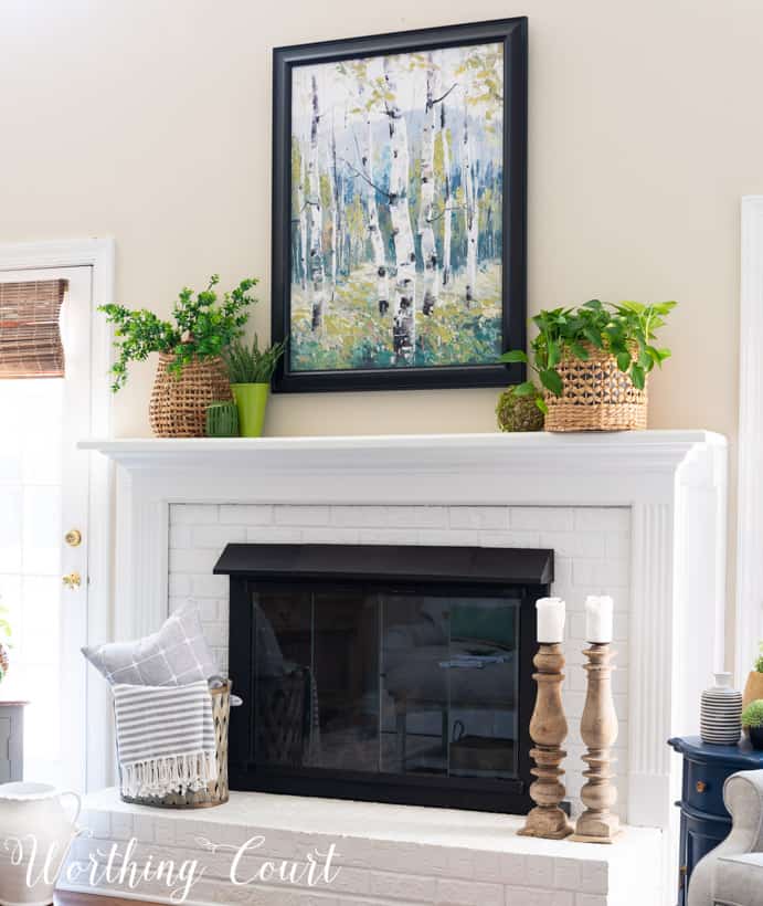 white brick fireplace with art, plants and baskets