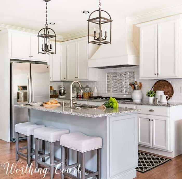 kitchen with white cabinets and gray island and stools