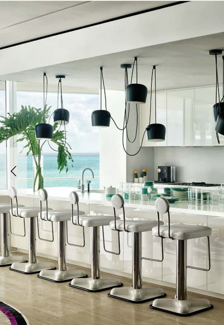 white kitchen with contemporary stools and black pendants