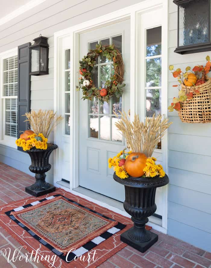 gray front door with fall wreath flanked with matching fall planters