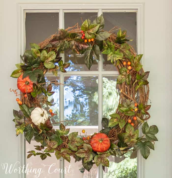 fall wreath with greenery, pumpkins and berries