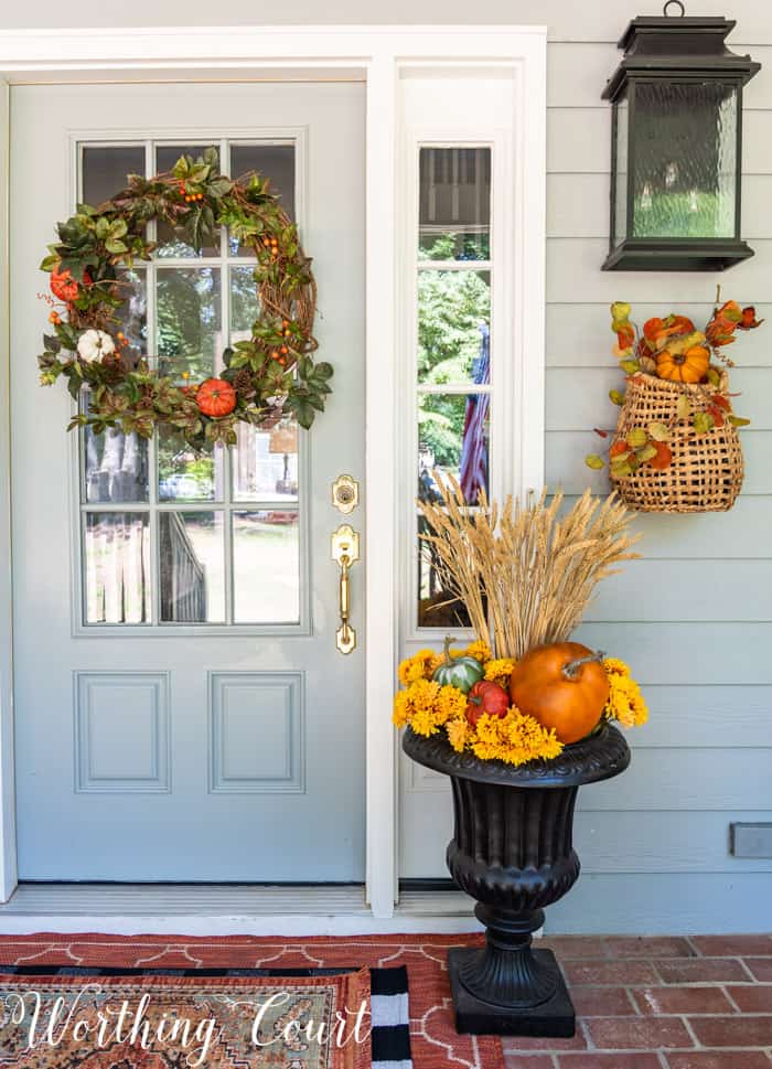 gray front door with fall wreath flanked with matching fall planters