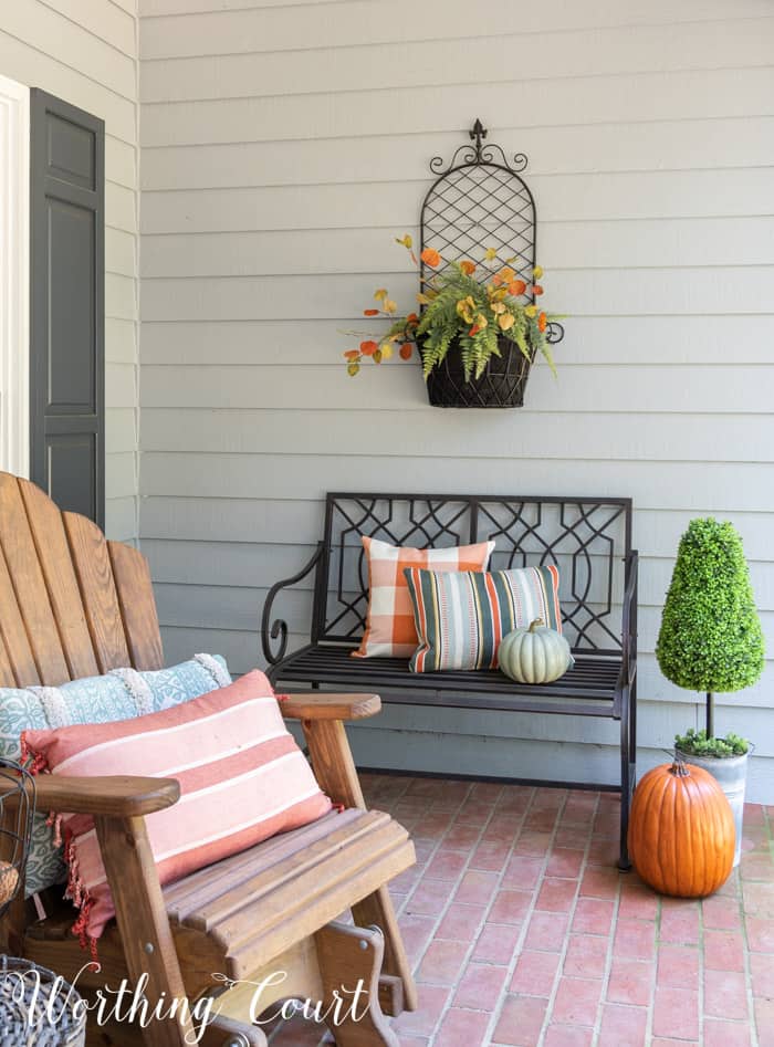 black outdoor bench with fall pillows and pumpkins