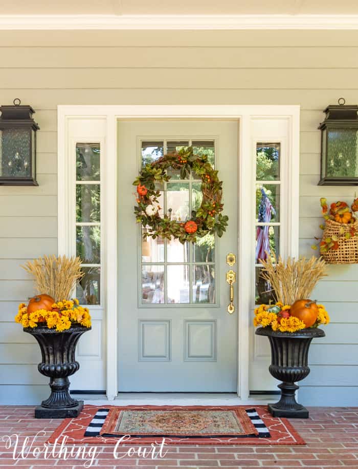 gray front door with fall wreath flanked with matching fall planters