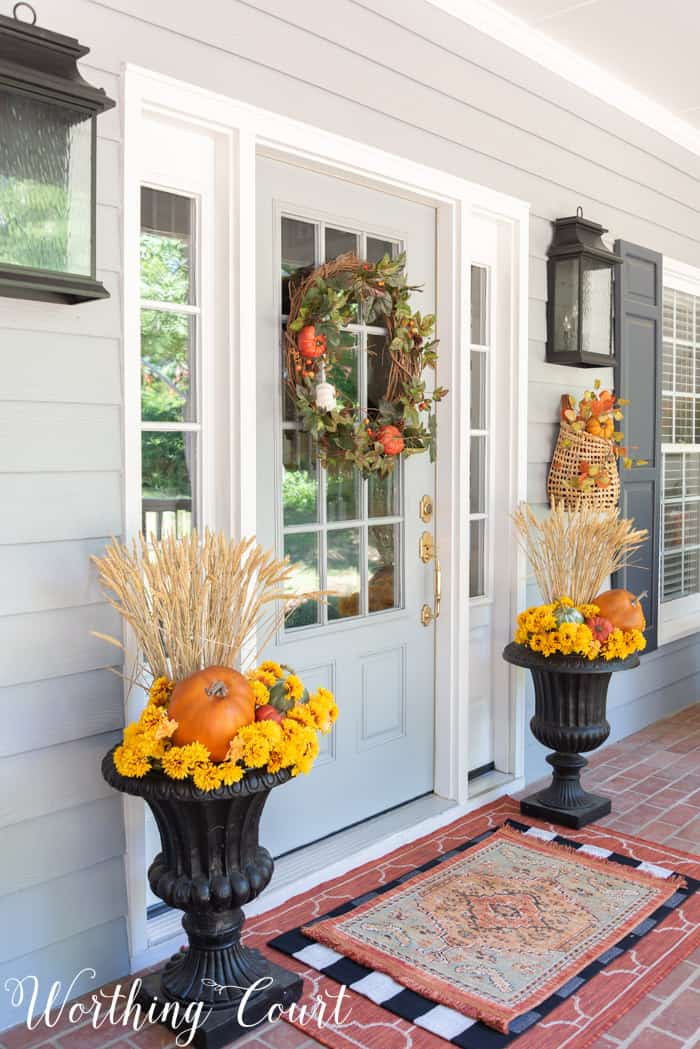 gray front door with fall wreath flanked with matching fall planters