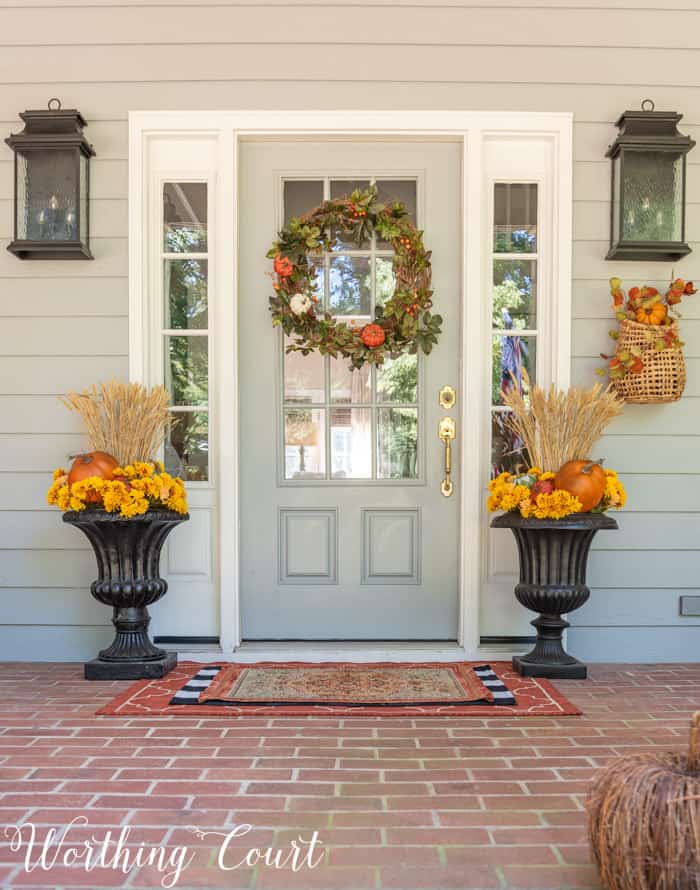 gray front door with fall wreath flanked with matching fall planters