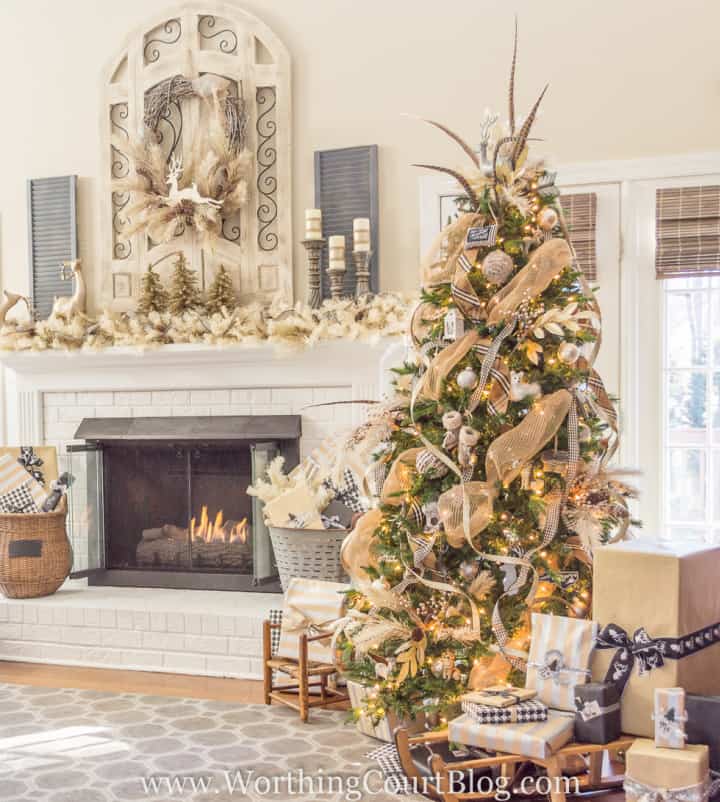 Christmas tree decorated with all neutral ornaments sitting beside fireplace