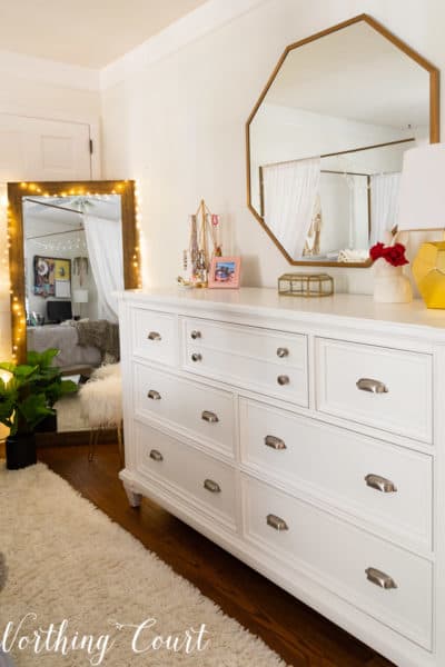 white dresser with octagonal mirror above