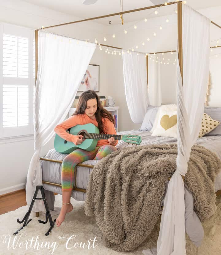 girl playing guitar sitting on the end of bed