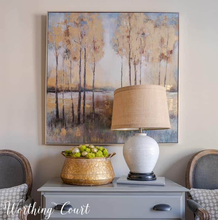 gray chest flanked by dining room chairs with artwork above