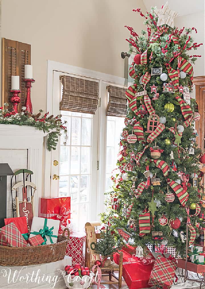 Christmas tree beside fireplace decorated with red and green ornaments and ribbon