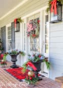 gray front door with Christmas wreath flanked by urns filled with Christmas decor