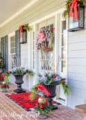 gray front door with Christmas wreath flanked by urns filled with Christmas decor