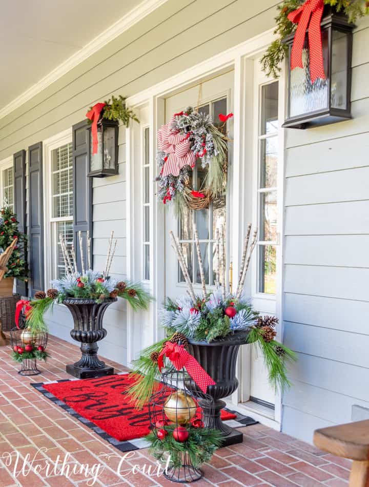 gray front door with Christmas wreath flanked by urns filled with Christmas decor