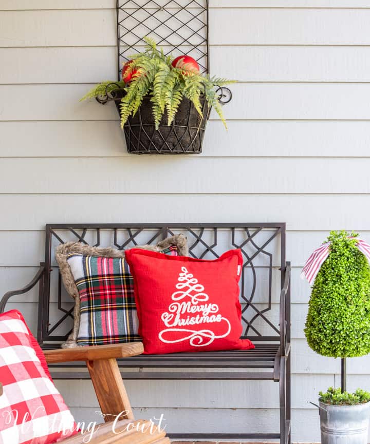 black outdoor bench with Christmas pillows