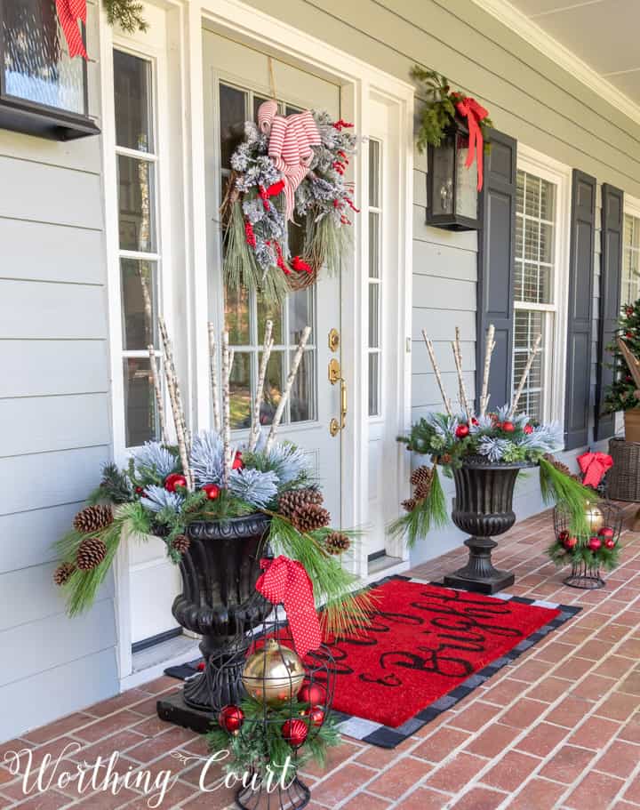 gray front door with Christmas wreath flanked by urns filled with Christmas decor