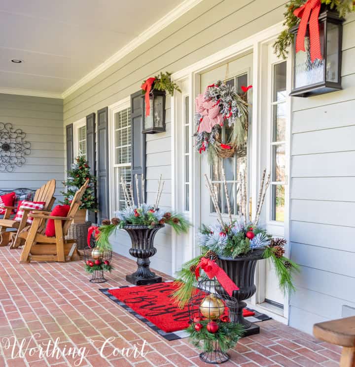 gray front door with Christmas wreath flanked by urns filled with Christmas decor