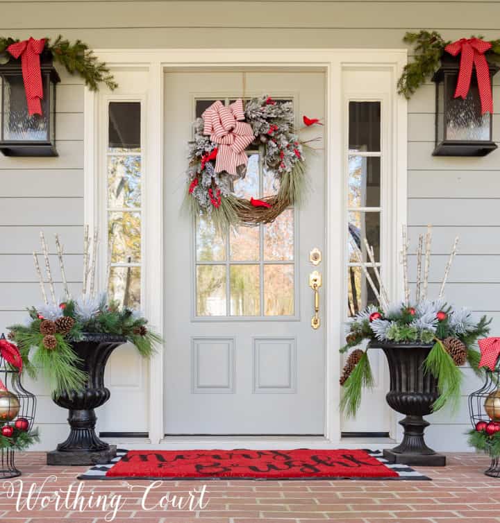 gray front door with Christmas wreath flanked by urns filled with Christmas decor