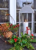 Christmas vignette with lantern, mini snowman, wire basket with orbs and faux greenery