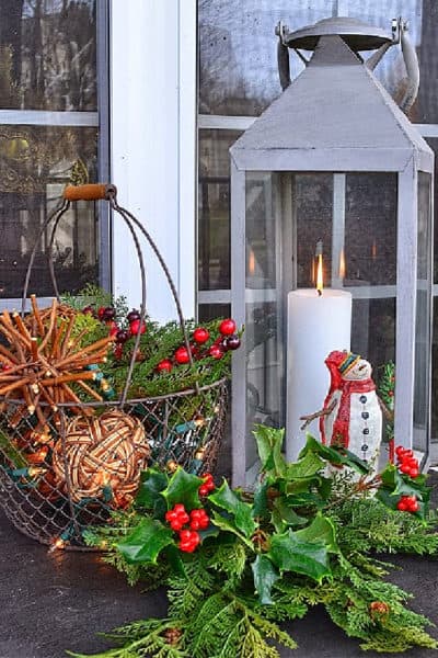 Christmas vignette with lantern, mini snowman, wire basket with orbs and faux greenery