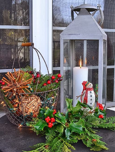 Christmas vignette with lantern, mini snowman, wire basket with orbs and faux greenery