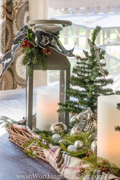 lantern with candle and mini Christmas tree in a wicker tray lined with a plaid scarf