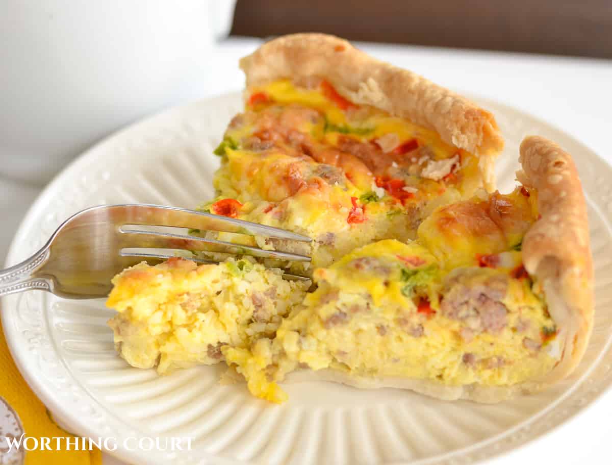 pieces of sausage and egg breakfast casserole on a white plate with a fork cutting into it