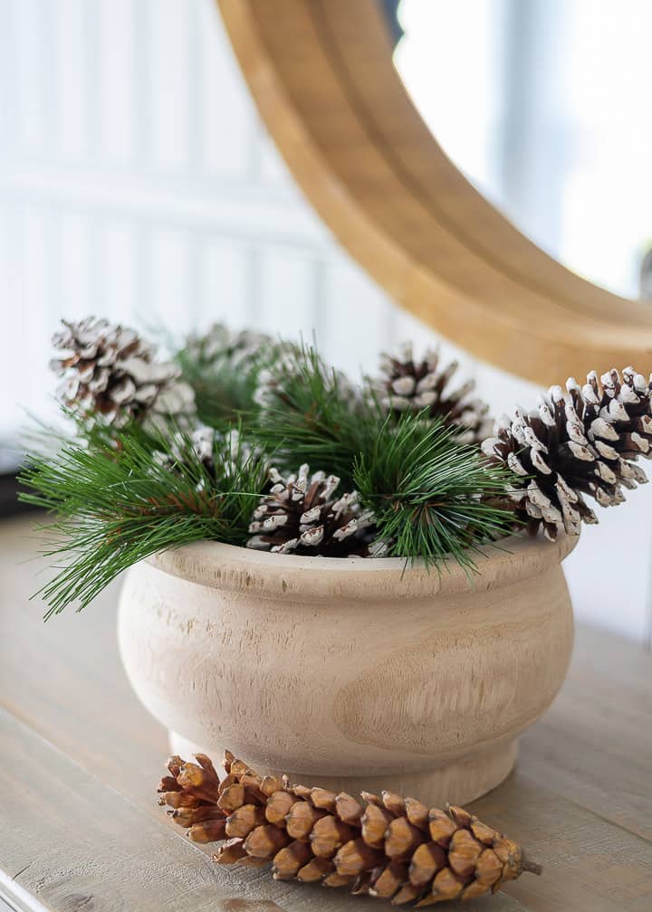 wooden bowl filled with evergreens and pinecones