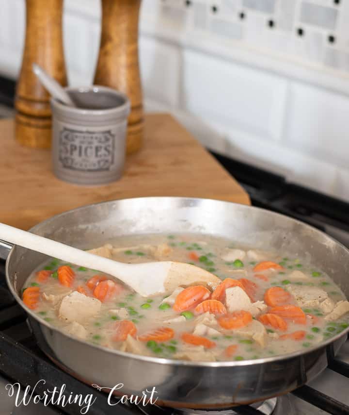 ingredients for chicken pot pie cooking in a skillet on the stove