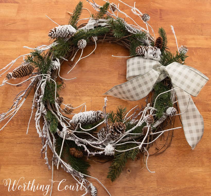 closeup of a winter wreath with snowy branches, pine branches and a bow