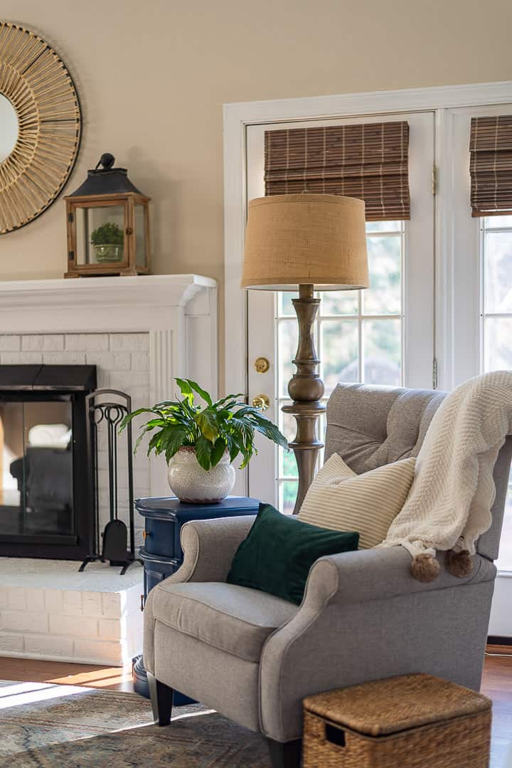 gray chair, floor lamp, blue side table sitting in front of windows and beside a white fireplace