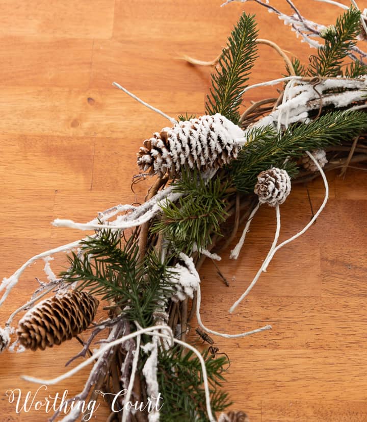 close up of snowy pinecones and pine branches on a grapevine wreath