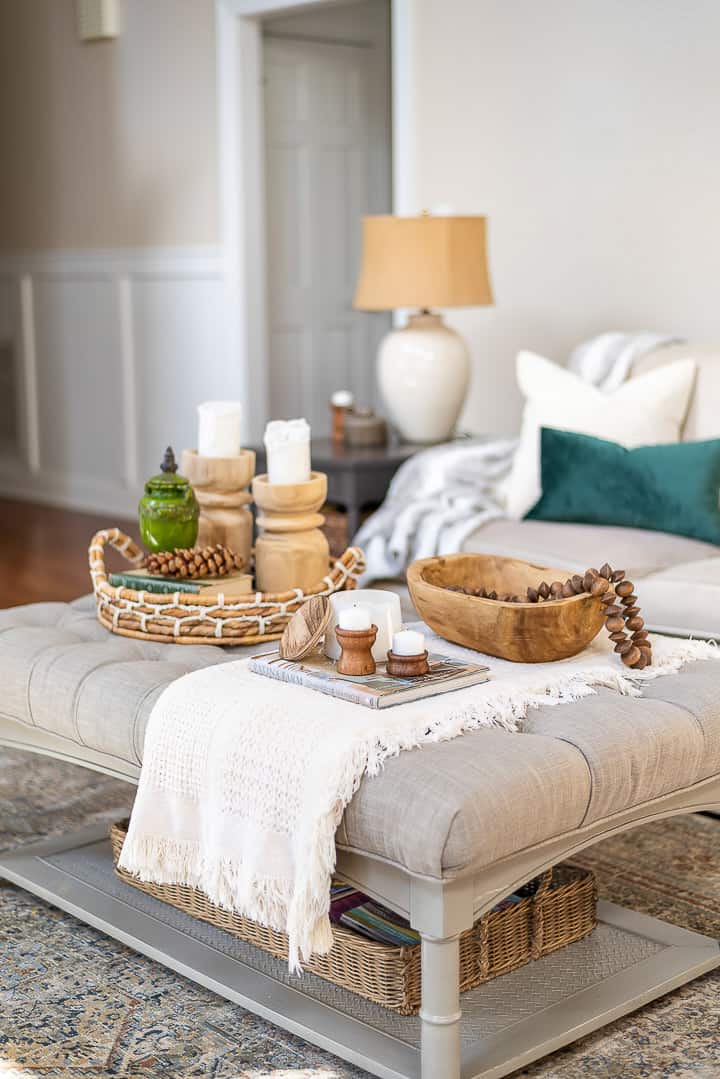 upholstered coffee table decorated with a folded throw and wood accessories