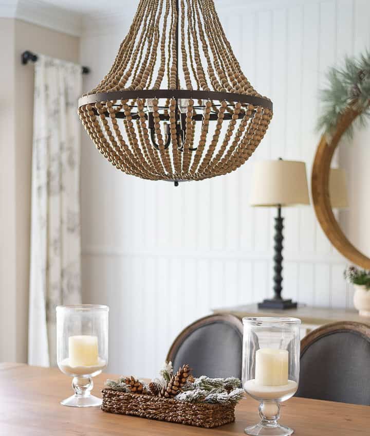 beaded chandelier above dining room table with a pair of glass lanterns for the centerpiece