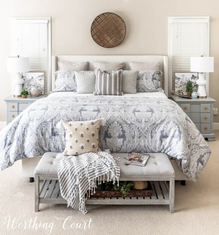 Kingsize-Bett mit blauer, weißer und grauer Bettwäsche und einer Bank am Fußende
