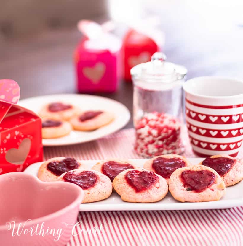 strawberry cookies on a white plate staged with other red and white items for Valentine's Day