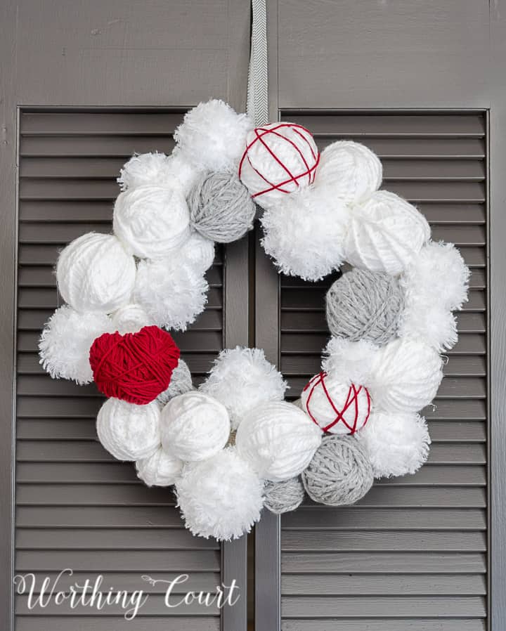 Valentine's Day wreath made with styrofoam balls covered with white and gray yarn and a heart cutout wrapped with red yarn