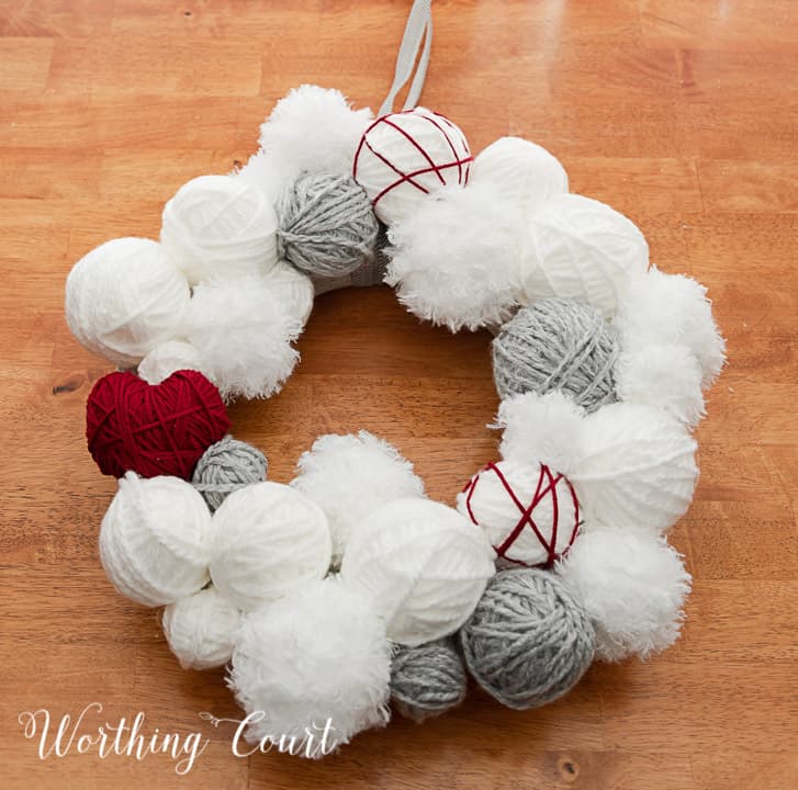 Valentine's Day wreath made with styrofoam balls covered with white and gray yarn and a heart cutout wrapped with red yarn