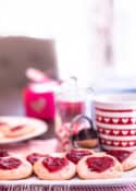 strawberry cookies on a white plate staged with other red and white items for Valentine's Day