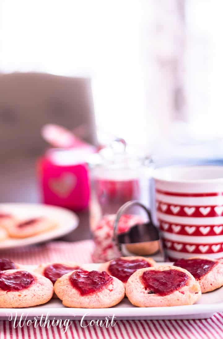 strawberry cookies on a white plate staged with other red and white items for Valentine's Day