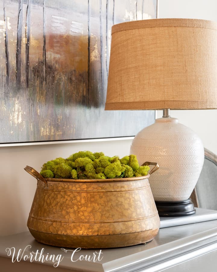 brass bowl filled with green moss on a small chest